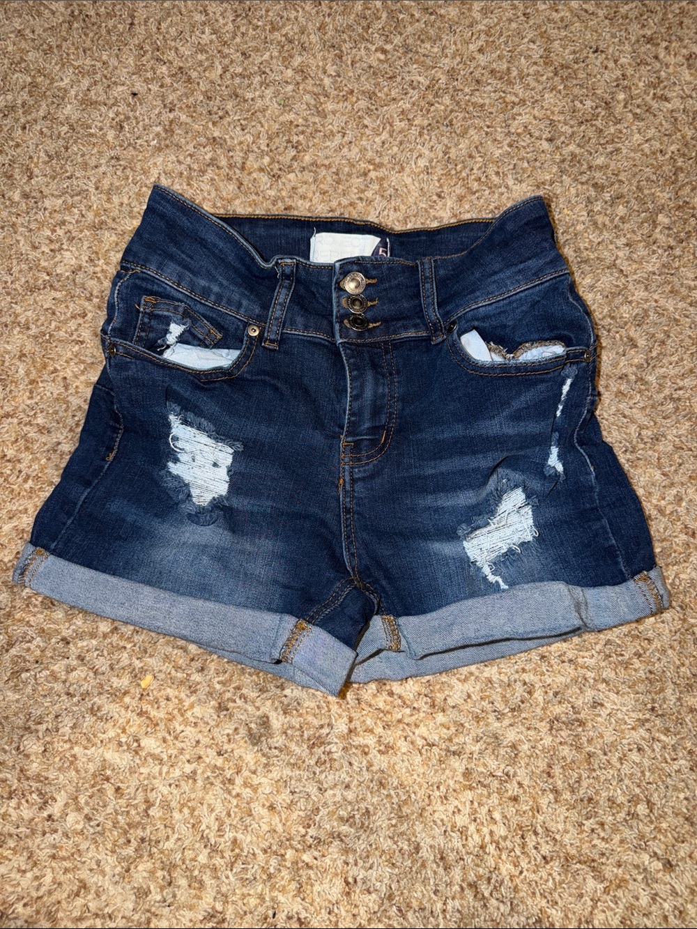 Project Rebel blue jeans feature a prominent three-button closure